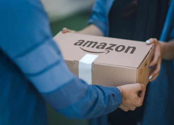 A DSP delivery driver hands an Amazon package to its recipient.